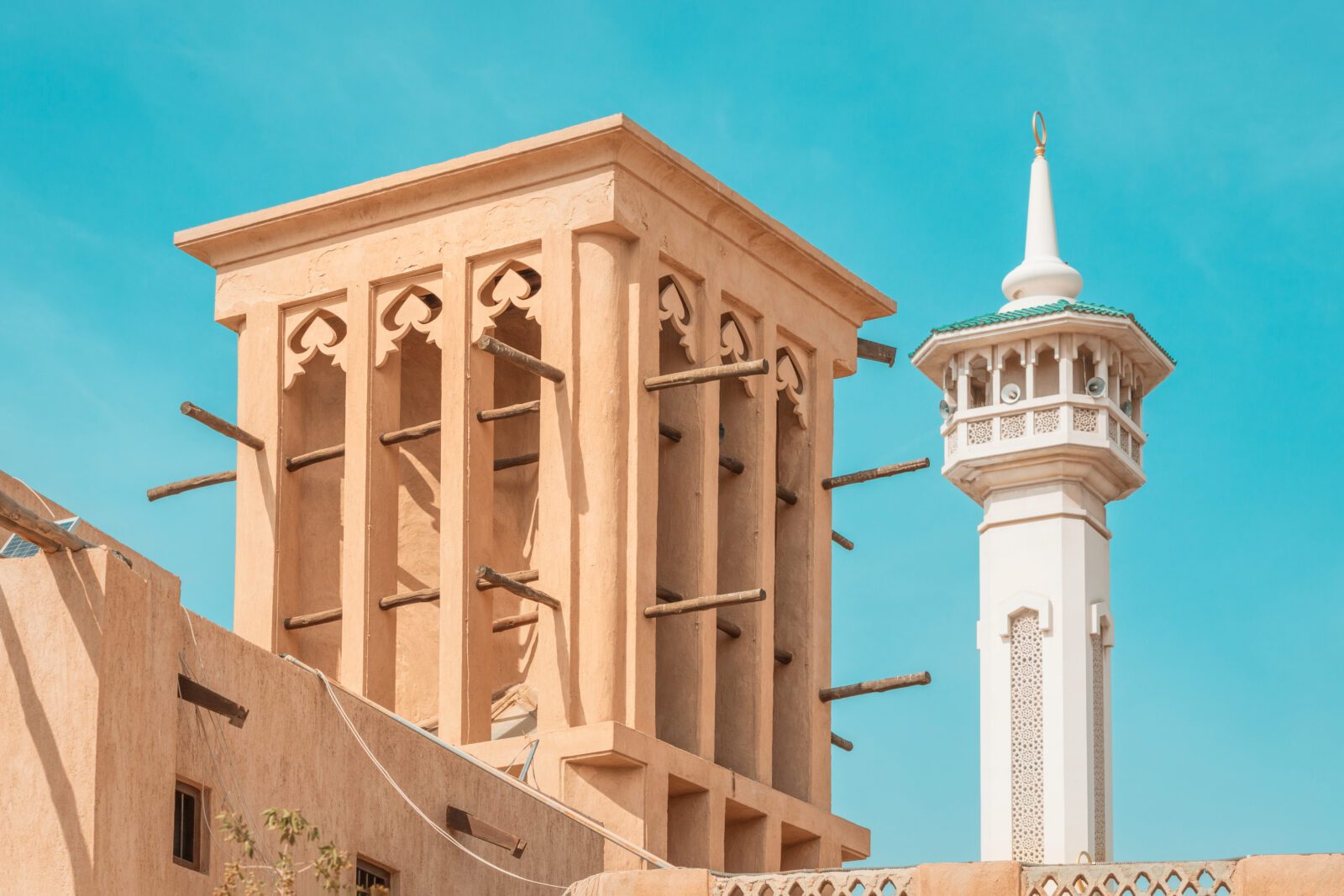 Al Fahidi mosque minaret and traditional arab windtower used for ventilation and air conditioning at historical district and neighbourhood in Bur Dubai